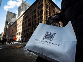 A woman holds a Hudson's Bay shopping bag in front of the Hudson's Bay Company (HBC) flagship department store in Toronto Jan. 27, 2014.