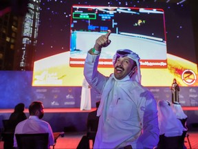 A man gestures as people watch a screen displaying information of the Hope Probe entering the orbit of Mars, in Dubai, United Arab Emirates, Feb. 9, 2021.
