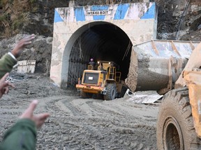 A bulldozer and rescue teams work at the entrance of a tunnel blocked with debris during rescue operations in Tapovan of Chamoli district, India, Monday Feb. 8, 2021 following a flash flood thought to have been caused when a glacier broke off on Sunday.