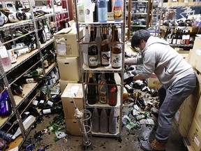 A worker cleans up broken bottles at a liquor shop after a strong quake in Fukushima, Japan, February 13, 2021.