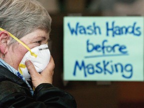 A woman puts on a protective mask to protect against SARS at a wash station at the entrance to North York General Hospital in Toronto in this May 26, 2003 file photo.