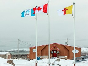 Flags of Iqaluit, Canada and Nunavut fly over the Elders' Qammaq, a drop-in centre, in Iqaluit, Nunavut, Nov. 18, 2020.