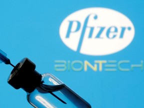 A vial and syringe are seen in front of a displayed Pfizer and Biontech logo in this illustration taken Jan. 11, 2021.