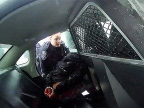 A Rochester police officer asks a handcuffed nine year old girl to get into a patrol car, prior to the girl being sprayed with a chemical irritant, in a still image from bodycam video taken in Rochester, N.Y., January 29, 2021.