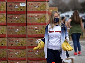 A Houston Texans cheerleader holds bananas as she waits to place them in a car during the Houston Food Bank food distribution at NRG Stadium on February 21, 2021 in Houston.