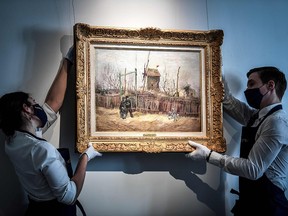 Two employees put on display a painting titled "Scene de rue a Montmartre" by Dutch painter Vincent Van Gogh, at the Sotheby's auction house in Paris on February 24, 2021.