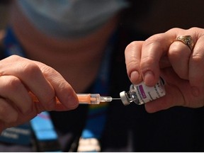 A healthcare professional draws up a dose of AstraZeneca/Oxford Covid-19 vaccine in a syringe at the vaccination centre set up at Chester Racecourse, in Chester, northwest England, on February 15, 2021.