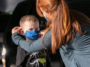 A teacher puts on a child's mask upon his arrival at Stark Elementary School in Stamford, Conn., Sept. 16, 2020.