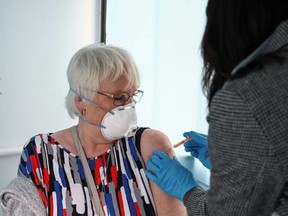 A woman receives a dose of the Oxford-AstraZeneca COVID-19 vaccine inside a bus modified into a mobile vaccination centre for the coronavirus disease (COVID-19), in Thamesmead, London, Britain, February 14, 2021.