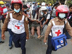Rescue workers carry an injured man after protests against the military coup, in Mandalay, Myanmar, February 20, 2021.