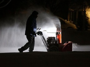Roger Hake gets an assist from his truck lights as he clears snow from his driveway before the sun comes up in Webster, near Rochester, New York, U.S. February 16, 2021.