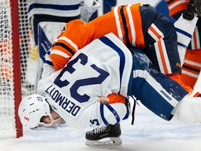 Oilers’ Josh Archibald (top) wrestles Maple Leafs’ Travis Dermott to the ice during the Leafs’ win on Monday.