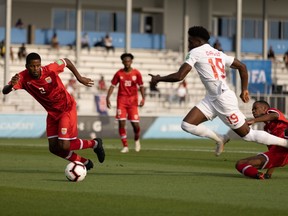 Alphonso Davies of Canada (No. 19) challenges Cameron Gray (No. 2) of the Cayman Islands in a 2022 FIFA World Cup qualifying game at the  IMG Academy in Bradenton, Fla., on Mar. 29. 2021.