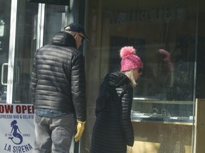 Window shoppers are pictured on Queen St. in the Beaches as they  peer at items in a store near Woodbine Ave. on March 7, 2021.