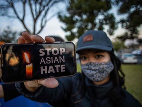 Julie Tran holds her phone during a candlelight vigil in Garden Grove, California, on March 17, 2021 to unite against the recent spate of violence targetting Asians and to express grief and outrage after yesterday's shooting that left eight people dead in Atlanta, Georgia, including at least six Asian women.