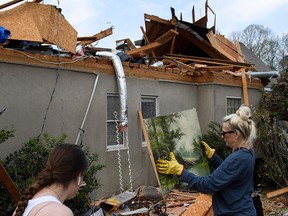 A volunteer picks up a painting found in debris surrounding a destroyed home on March 26, 2021, following a tornado that hit the Eagle Point community on south of Birmingham, Alabama.