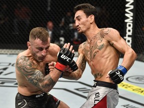 In this handout image provided by UFC, Max Holloway, right, punches Alexander Volkanovski of Australia in their UFC featherweight championship fight during the UFC 251 event at Flash Forum on UFC Fight Island on July 12, 2020 on Yas Island, Abu Dhabi, United Arab Emirates.