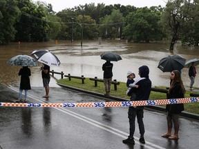 People gather on a flooded street in the suburb of Windsor as the state of New South Wales experiences widespread flooding and severe weather, in Sydney, Australia, March 22, 2021.