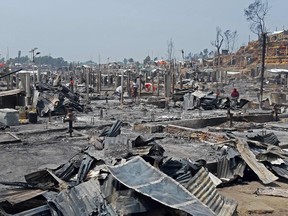 People are seen amidst the debris at a Rohingya refugee camp in Ukhia on March 23, 2021 after a huge blaze forced around 50,000 people to flee.