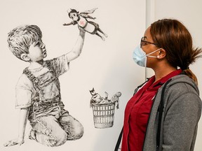 A handout picture from University Hospital Southampton on May 7, 2020 shows a member of staff posing with an artwork by street artist Banksy called "Game Changer.”
