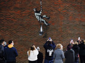 People take pictures of a new mural by Banksy on a wall at HM Reading Prison in Reading, Britain, March 1, 2021.