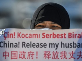 A member of the Uighur minority holds a placard as they demonstrate to ask for news of their relatives and to express their concern about the ratification of an extradition treaty between China and Turkey, Feb. 22, 2021 near the China consulate in Istanbul, Turkey.
