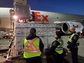 Canada Border Services Agency personnel watch as a shipment of the newly authorized AstraZeneca vaccine arrives at an airport in Canada March 3, 2021.