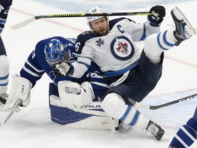 Winnipeg Jets' Blake Wheeler tumbles into Maple Leafs goaltender Frederik Andersen during the third period in Toronto on Thursday, March 11, 2021.