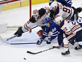 Oilers goaltender Mike Smith covers the net during scramble in front with Maple Leafs centre William Nylander at the Scotiabank Arena last night.