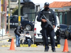 Police officers work at a crime scene where gunmen killed at least 13 Mexican police officers in an ambush, in Coatepec Harinas, Mexico, Friday, March 19, 2021.