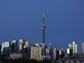 The CN Tower stands at dusk above office buildings and condominiums in the downtown core of Toronto on Sept. 20, 2020.
