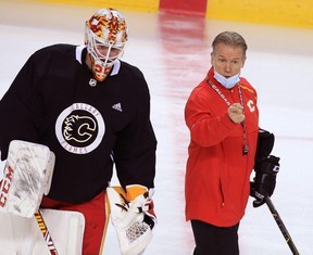 Flames goalie Jacob Markstrom listens as former head coach Geoff Ward instructs the players at practice. POSTMEDIA NETWORK