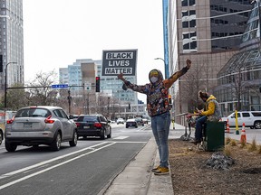 An activist holds a sign outside the Hennepin County Government Center as jury selection continues in the trial of former police Derek Chauvin, who is facing murder charges in the death of George Floyd, in Minneapolis, Minnesota, March 22, 2021.