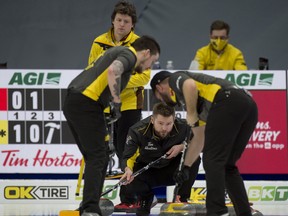 Team Manitoba's Jason Gunnlaugson (back) looks on as Team Wild Card 1 skip Mike McEwen watches as Coling Hodgson (left) and Derek Samagalski bring the stone into the house during Draw 8 at the Brier on Monday.