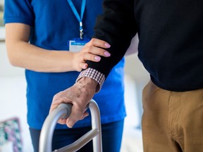 A senior is aided by a care worker.