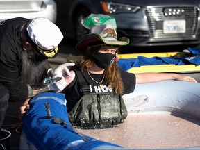 Stuntman Hunter Ray Barker gets a logo of of the restaurant tattooed on his arm as he sits partially submerged in a bean dip tub to raise awareness for Los Toros Mexican Restaurant during the outbreak of COVID-19, in Chatsworth, Calif., March 8, 2021.