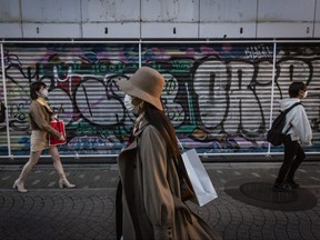 People wearing face masks walk past a closed shop along the Takeshita shopping street on Feb. 28, 2021 in Tokyo, Japan.