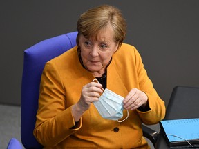 German Chancellor Angela Merkel puts her protective mask on during a plenum session of the lower house of parliament, the Bundestag, in Berlin, Germany, March 24, 2021.