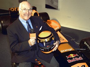 Ex-commentator Murray Walker poses for the cameras on an F1 racing car.