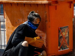 A protester takes shelter behind a rubbish bin adorned with an image of Myanmar armed forces chief Senior General Min Aung Hlaing during a demonstration against the military coup in Yangon on March 8, 2021.