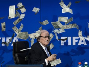 This file photo taken on July 20, 2015 shows then FIFA president Sepp Blatter looking on with fake dollar notes flying around him thrown by a protester during a press conference at the football's world body headquarter's in Zurich.