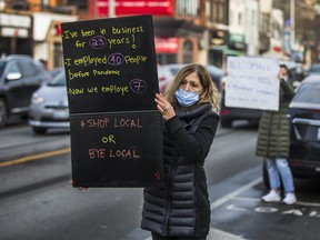Olga Parussis, hold up a sign in front of her restaurant , Pantheon, to remind passing cars of the important of small business in Toronto on Friday December 11, 2020.