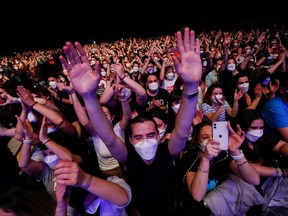 Spectators wearing protective masks attend a concert of "Love of Lesbian" at the Palau Sant Jordi, the first massive concert since the beginning of the COVID-19 pandemic in Barcelona, Spain, March 27, 2021.