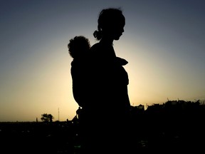 An Ethiopian woman who fled the ongoing fighting in Tigray region carries her child near the Setit river on the Sudan-Ethiopia border November 22, 2020.