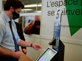 Canada's Prime Minister Justin Trudeau receives a demonstration of how the check-in system works while he visits a vaccination clinic.