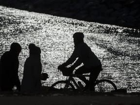 A cyclist and pedestrians share the trail along the Martin Goodman Trail along the shore of Lake Ontario near the Humber River in Toronto, Ont. on Sunday, Feb. 7, 2021.