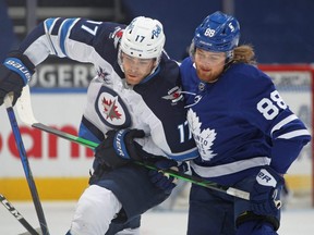Jets forward Adam Lowry, left, is held up by Maple Leafs forward William Nylander during NHL action at Scotiabank Arena in Toronto, Saturday, March 13, 2021.