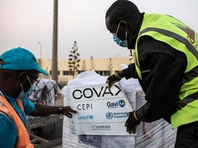Workers start to un-wrap boxes containing Oxford/AstraZeneca vaccines donated to Senegal by the Covax global COVID-19 vaccination program as they are unloaded in Dakar on March 3, 2021.