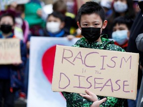 Ethan Yang, 11, holds a sign reading "racism is the disease" during a "Kids vs. Racism" rally against anti-Asian hate crimes at Hing Hay Park in the Chinatown-International District of Seattle, Washington, U.S. on March 20, 2021.