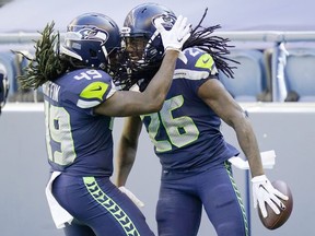 Seattle Seahawks cornerback Shaquill Griffin (26) is greeted by his twin brother, outside linebacker Shaquem Griffin (49) after Shaquill Griffin intercepted a pass against the Dallas Cowboys during the first half of an NFL football game, Sunday, Sept. 27, 2020, in Seattle.